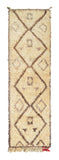 Overhead view of a perfectly imperfect, deeply plush handmade 1970s vintage Beni Ourain Moroccan wool runner rug named Faraway Land (2' x 6'10") featuring a thick cream base covered in earthy brown geometric diamonds containing small, abstract tribal symbols, a slightly wavy edge, and a tiny pop of red fringe at the bottom right, with a 1-inch pile.