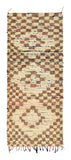 Overhead view of a captivating handmade vintage Beni Ourain Moroccan wool runner rug named Underneath (3'2" x 7'8") featuring a cream base with a stepped, checkerboard diamond pattern in earthy brown, with dark foundation lines and tiny pops of neon color showing through, with a 3/4-inch pile.