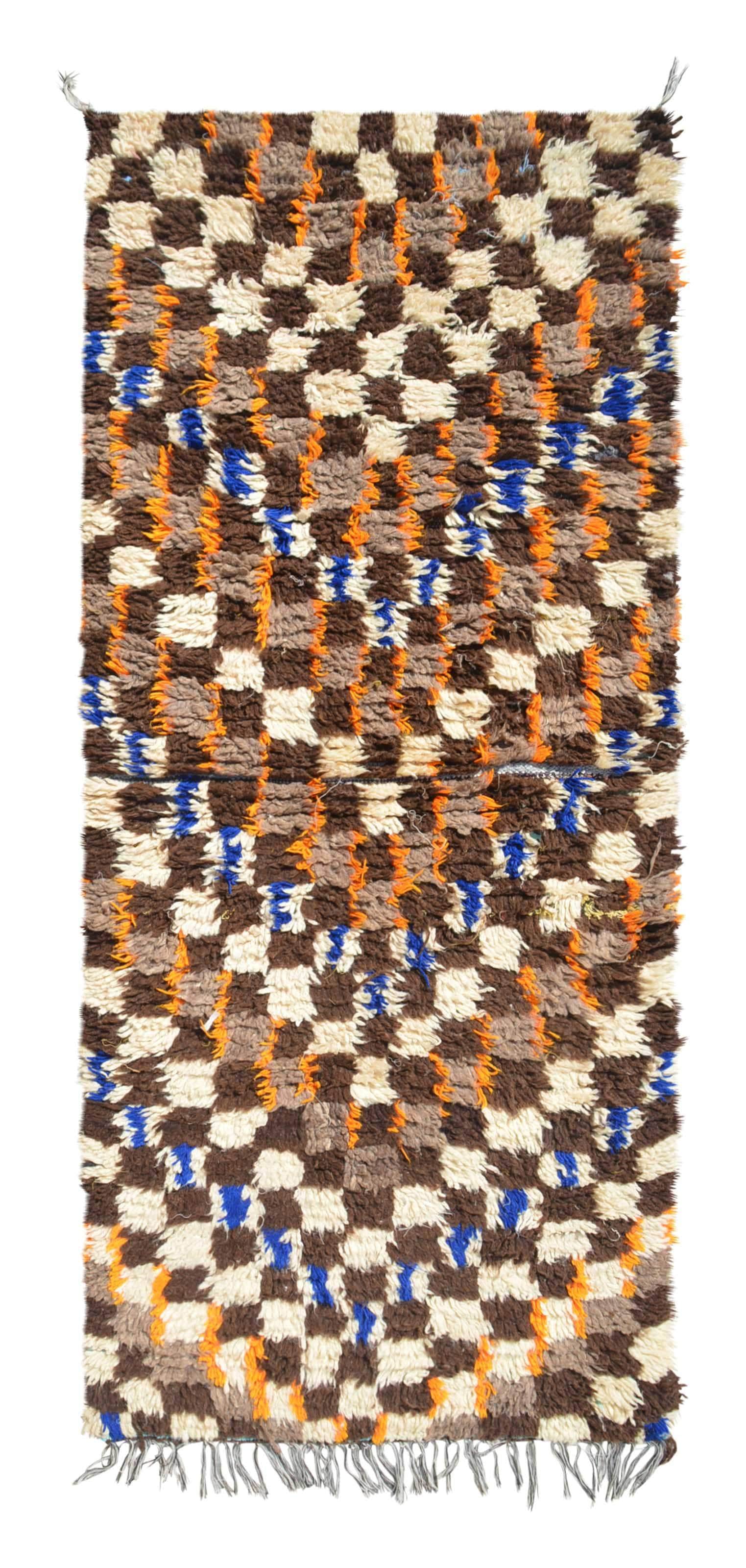 Overhead view of a deeply plush, highly textured handmade 1970s vintage Azilal Moroccan wool and cotton accent rug named The Groove (2'10" x 6'4") featuring an edge-to-edge earthy checkerboard pattern in brown, taupe, and cream, overlaid with squiggly vertical lines of bright orange and cobalt blue yarn, with a 3/4-inch pile.