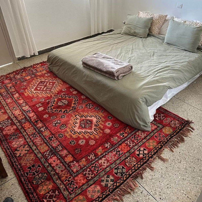 Vintage red Moroccan Berber rug with diamond medallions in a bedroom