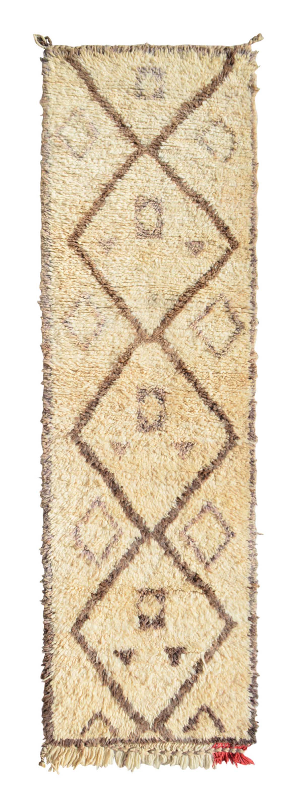 Overhead view of a perfectly imperfect, deeply plush handmade 1970s vintage Beni Ourain Moroccan wool runner rug named Faraway Land (2' x 6'10") featuring a thick cream base covered in earthy brown geometric diamonds containing small, abstract tribal symbols, a slightly wavy edge, and a tiny pop of red fringe at the bottom right, with a 1-inch pile.