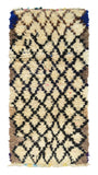 Overhead view of a deeply plush, high-contrast handmade 1960s vintage Moroccan wool and cotton runner rug named High Stakes (3'4" x 7') featuring a thick cream base covered in a heavy black wobbly geometric diamond lattice, framed by earthy brown side borders and vivid royal blue top corners, with a 3/4-inch pile.